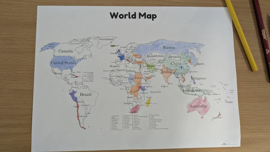 The paper world map with countries coloured in by visitors in coloured pencil